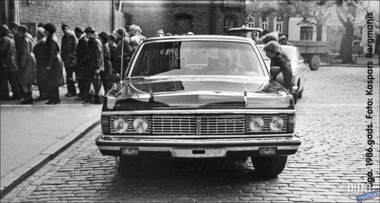 1986.oktobris. Rīga. Pirmā „GAZ 14” Latvijā. Limuzīns no LSPR komunistiskās partijas garāžas. Numura zīme uz priekšējā pampera nav pat uzstādīta. Pavadošais automobilis „GAZ 24” no Valsts drošības komitejas (KGB).  Šāda eskorta pavadībā uz Doma baznīcu, klausīties ērģeļmūzijas koncertu tika atvests kāds augsta ranga kompartijas „čiekurs” no Maskavas. 
Foto no Kaspara Bergmaņa arhīva.
